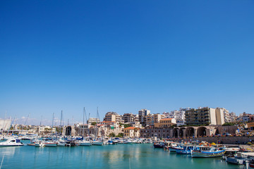 The harbor of Heraklion with ruins of Venetian era buildings and numerous yachts and boats in port, Crete, Greece.