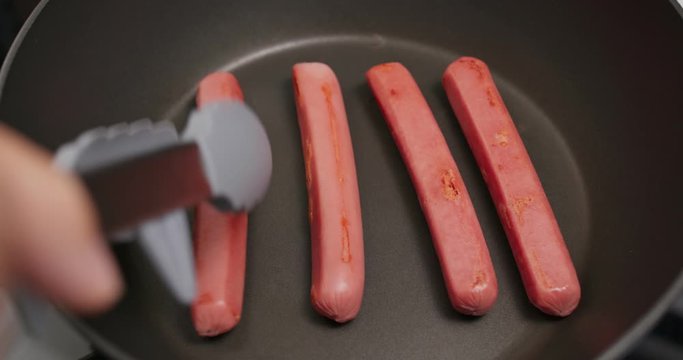 Cooking sausages on the fry pan in kitchen for breakfast