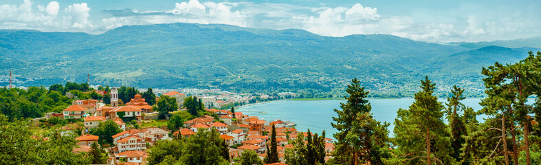 North macedonia. Ohrid. Different buildings and houses with red roofs on lake shore on mountains background - obrazy, fototapety, plakaty