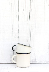 Enameled mugs in retro style on an old wooden background.