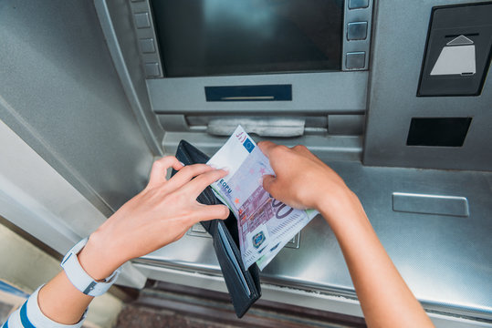 top view of woman putting money in wallet near atm machine