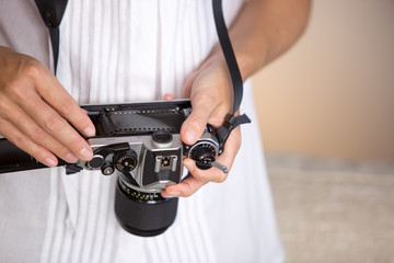 Contrast between old and modern times: a young woman fiddles with her vintage camera hanging from her neck