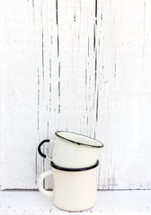 Enameled mugs in retro style on an old wooden background.