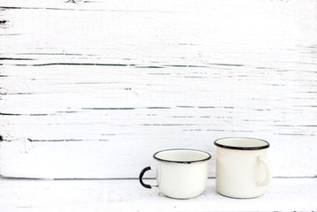 Enameled mugs in retro style on an old wooden background.