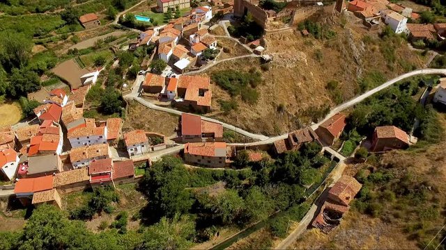 Aerial drone footage of medieval Aragon village of Vozmediano and castle ruins with Moncayo mountains in the background .