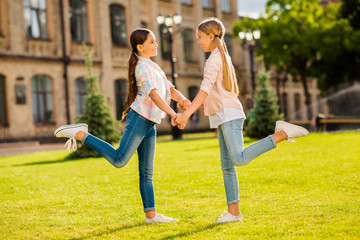 Profile side full length body size view of two nice attractive cheerful cheery friendly pre-teen girls wearing casual having fun spending vacation holiday weekend sight seeing landmark