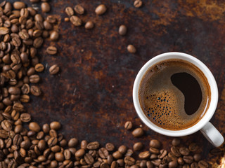 white espresso coffee Cup and roasted beans on old rusty brown background. copy space