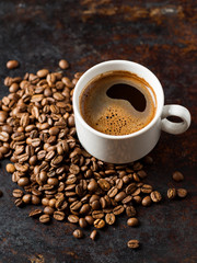 Tasse de café expresso blanc et grains torréfiés sur fond brun rouillé