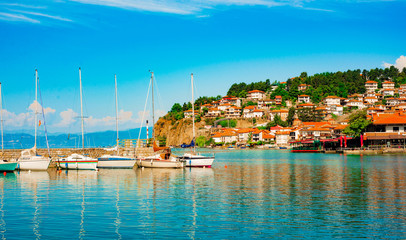 North macedonia. Ohrid. Pier with different sailboats and hill with buildings - obrazy, fototapety, plakaty