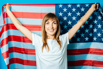 Young woman holds the USA flag on a blue background. USA Visa Concept, English, Independence Day, July 4th, Memorial Day. Travel to the USA