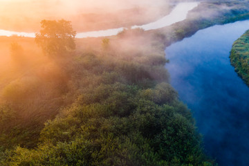 Blue river flows along rural area on foggy morning. Ecology concept