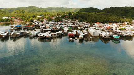 Old wooden house standing on the sea in the fishing village, aerial view. Dapa, Siargao, Philippines.