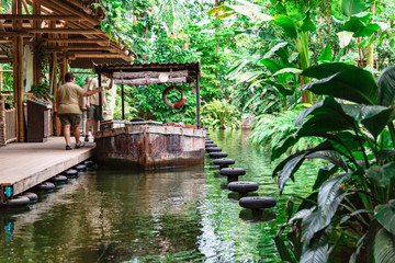 Tourists board old boat moored to pier in jungle