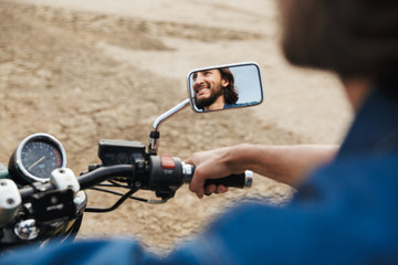 Man biker on his bike outdoors on a beach. Focus on mirror.