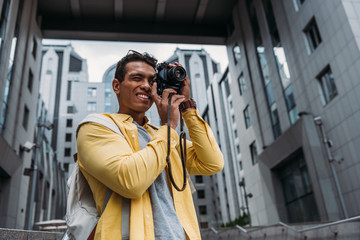 Fototapeta na wymiar Bi-racial man taking photo on digital camera near buildings