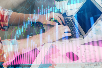 Double exposure of stock graph with businessman typing on computer in office on background. Concept of hard work.