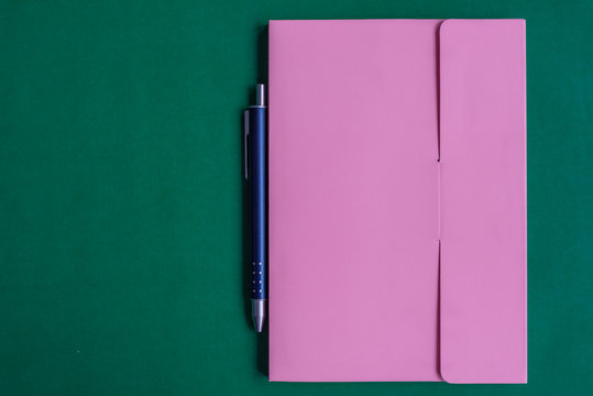 The notebook and pen is on green paper background