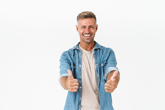 Photo of successful guy in denim shirt rejoicing and gesturing thumbs up