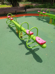 Green seesaws with pink seats in a playground