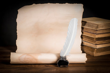 Fountain pen with inkwell on the background of scrolls of papyrus and books