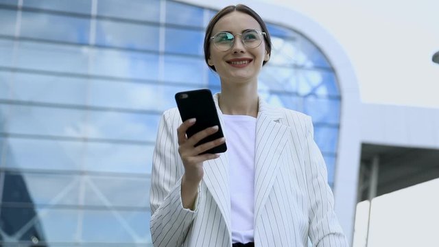 Business Woman With Phone On Street. Portrait Of Smiling Beautiful Young Female In Stylish Clothes Calling On Smartphone, Standing Near Office. High Quality Image.