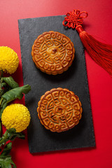 Chinese Mid-Autumn Festival cuisine, moon cakes and chrysanthemums on red background