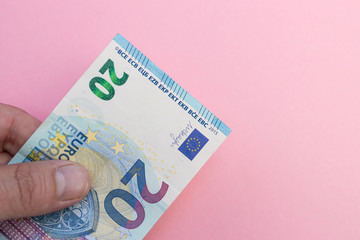 Hand holding Euro currency cash bank notes money pink background