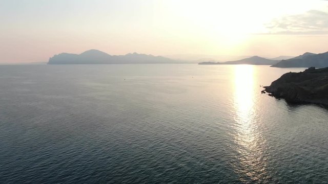 Landscape frome the blue and pink mountains at dusk Setting sun is reflected in seawater aerial drone shot KOKTEBEL CRIMEA AUGUST 2019