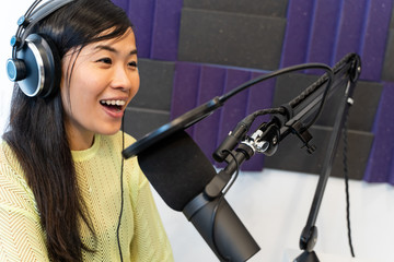 Asian woman happy talking on air at the radio station.