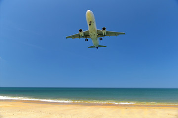 Fototapeta na wymiar Commercial plane landing at Phuket International Airport on tropical beach and blue sky background, travel concept and business transportation idea