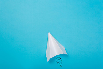 Flat lay of white paper airplane and blank paper on blue background.