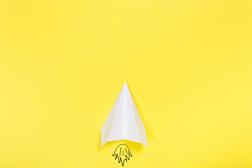 Flat lay of white paper plane and blank paper on yellow