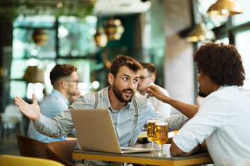 Men are sitting at table in modern cafe. Talk about work