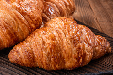 Fresh fragrant crispy french croissants on a wooden board. Delicious pastries for a refined breakfast