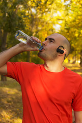 Young guy refreshing after exercise in park
