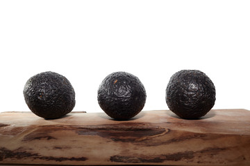 three avocados on a wood with white background