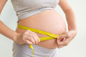 Pregnant woman measures her stomach. Pregnancy and weight gain. Pregnancy and sport. Big belly. Trimester.