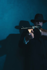 Fototapeta premium Retro gangster in hat shoots with machine gun.