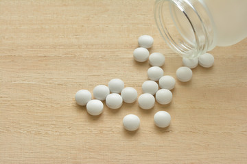 Fototapeta na wymiar White pills on a wood table
