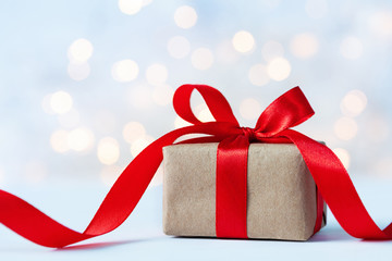 Christmas gift box against light bokeh background. Holiday greeting card.