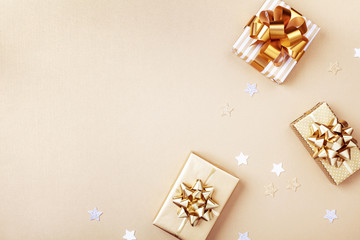 Gift or present boxes and stars confetti on golden table top view. Flat lay composition for birthday, christmas or wedding.