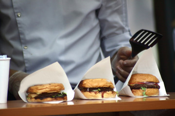 three ready-to-eat hamburgers in paper cover in the cafe - obrazy, fototapety, plakaty