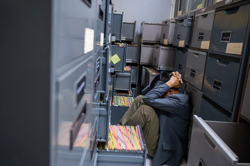 Business people are stressed from work sitting next to a file cabinet at the office..