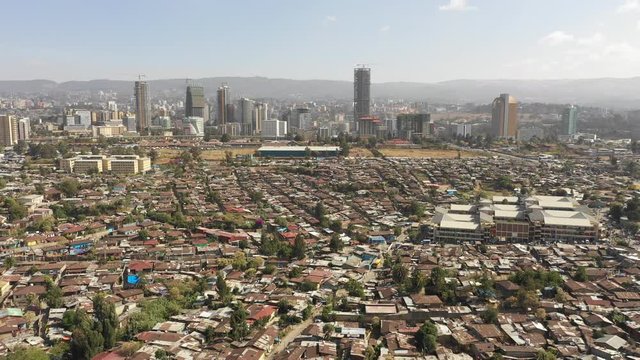 Retreating aerial footage flying over low-rise residential neighborhoods contrasting with commercial office towers and skyline Addis Ababa, changing urban landscapes Ethiopia Africa