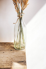 Still life of a bouquet of dried flowers in a glass bottle on a wooden table. Place for text or advertising