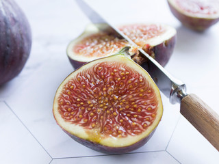 ripe figs with a knife on a marble table