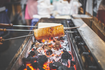 Chimney cakes (Kurtoskalacs) cooking on ember on Christmas market.