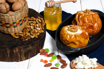 healthy food. Baked apples with cottage cheese and nuts lie in a black baking dish on a white wooden table