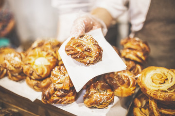 Man hand holding golden colored pastry rolls in bakery.