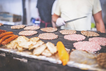 Man preparing burgers at street festival.